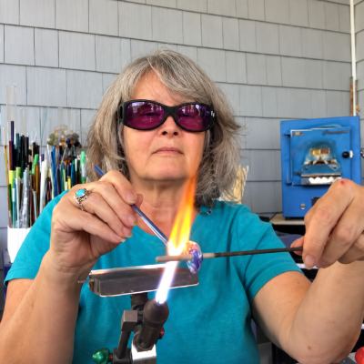 Blonde woman wearing dark protective eyewear heating glass